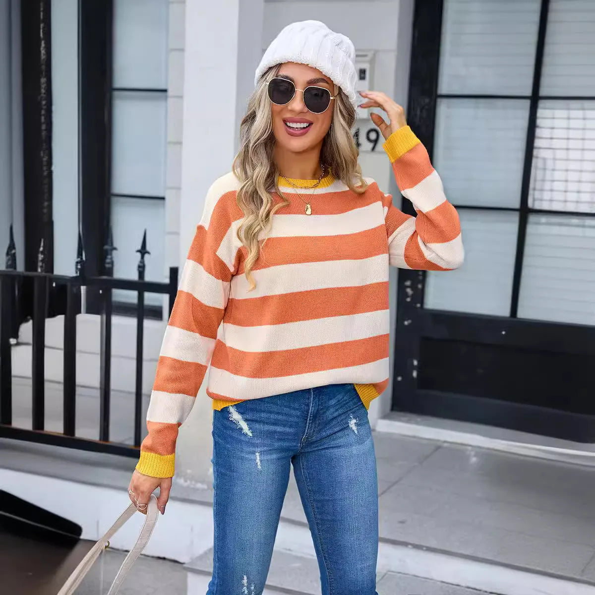 Women's loose fit acrylic sweater in blue with stripes, showing round neck and long sleeves.