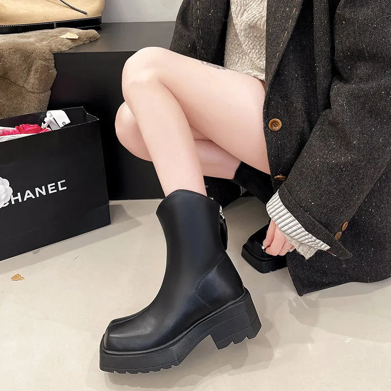 Black women's platform Martin boots with a square toe and back zipper on a wooden floor.