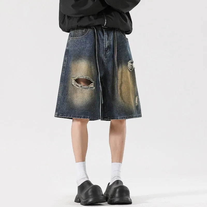Man wearing retro blue loose fit ripped denim jeans with distressed details.