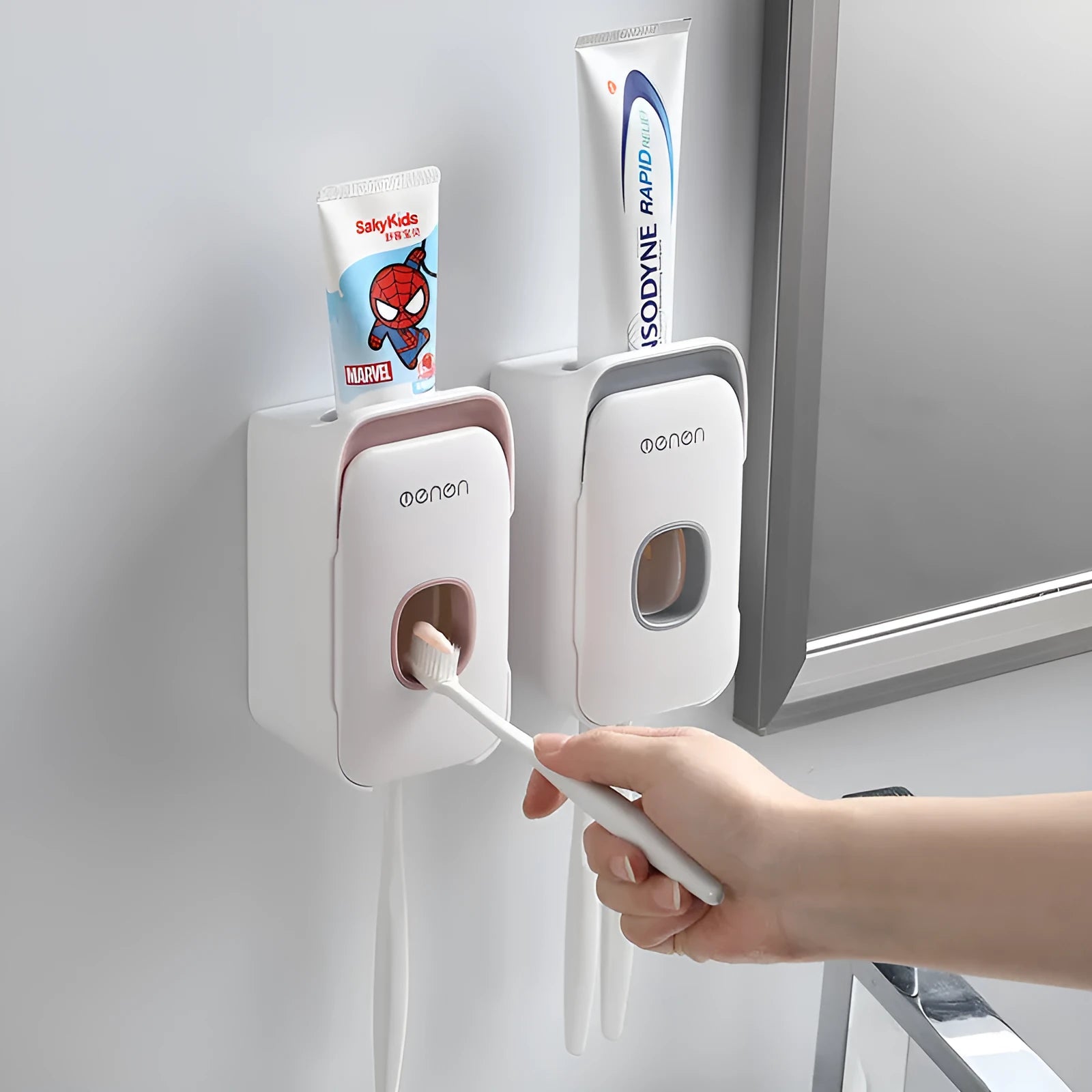 Blue automatic toothpaste dispenser mounted on a bathroom wall with a toothbrush below.