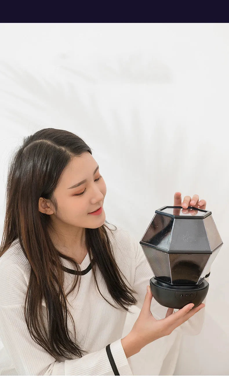 Children's rotating stars LED night light projecting coloured star patterns on bedroom wall