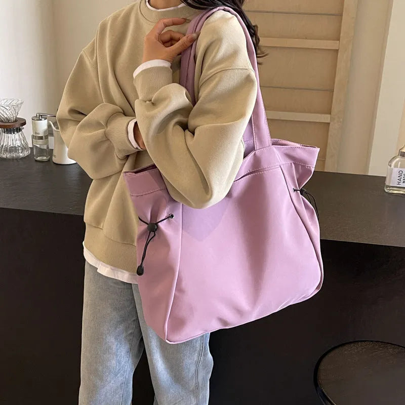 Soft Oxford cloth folding commuter tote bag shown in one of five colours: black, brown, dark grey, light grey or purple.