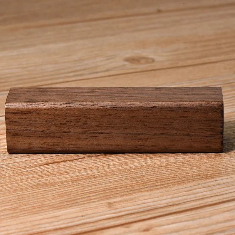 Black walnut wood portable power bank showing natural grain, with dimensions 100mm by 25mm.