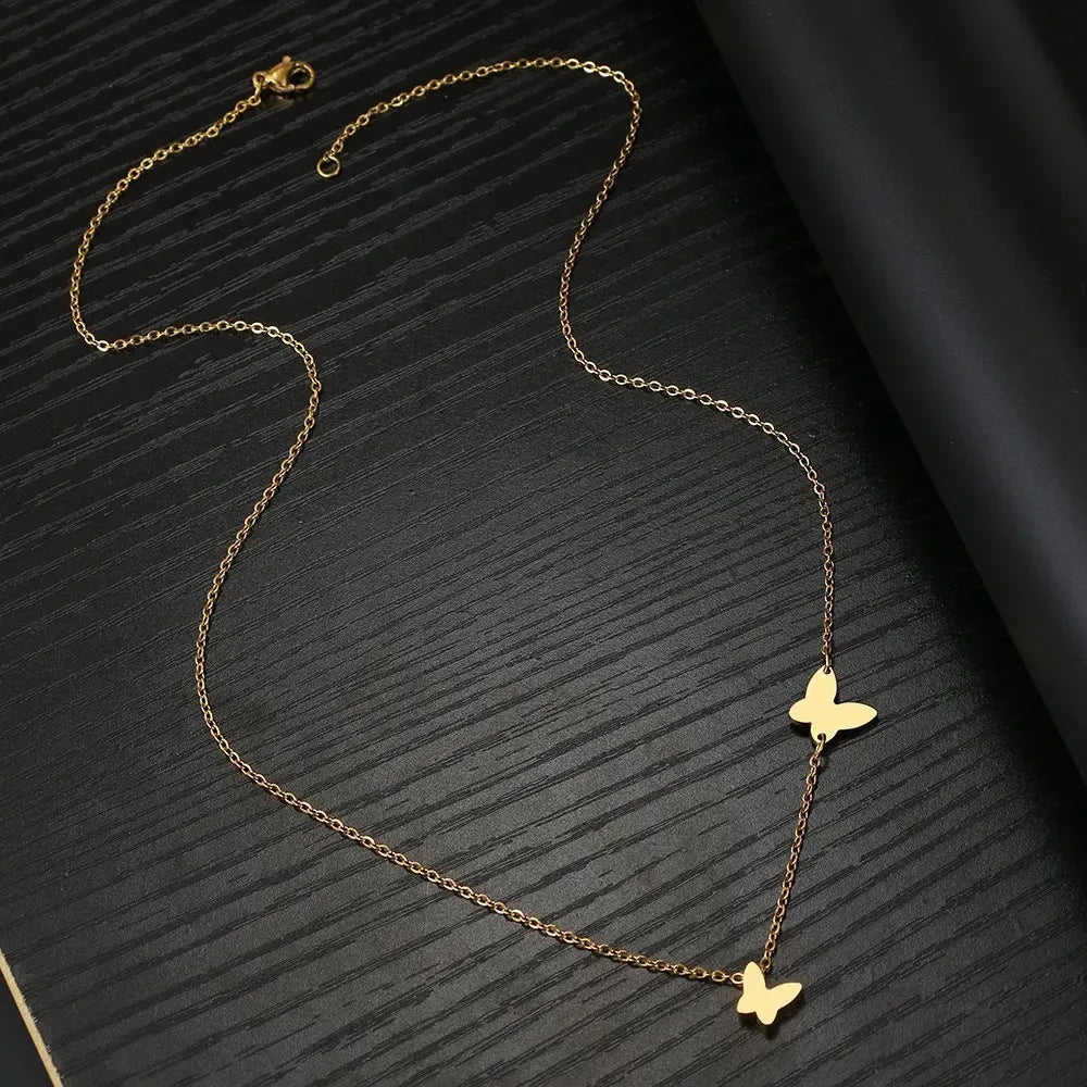 Butterfly pendant necklace in stainless steel with 18K gold electroplated finish on a white background