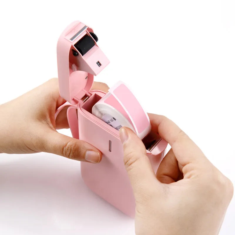 Compact D11 Bluetooth thermal label printer in black, white, pink, or green with smartphone showing label design app.