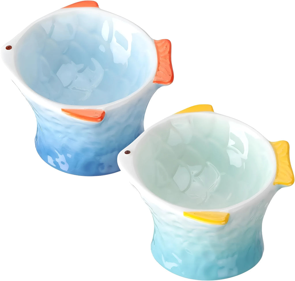 Set of four coloured fish-shaped ceramic cat bowls with a tilted, elevated design on a table.