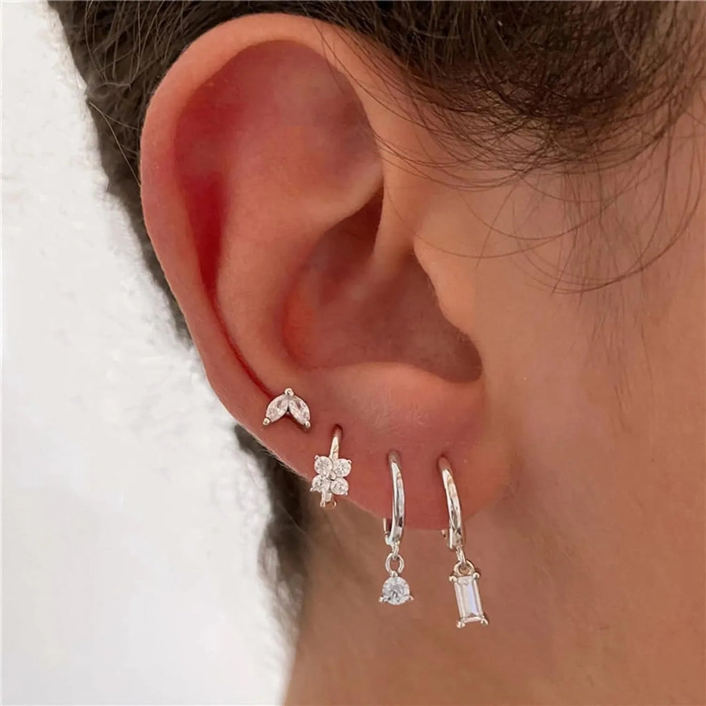 Set of four pairs of geometric copper earrings with zircon details in gold and silver colours.