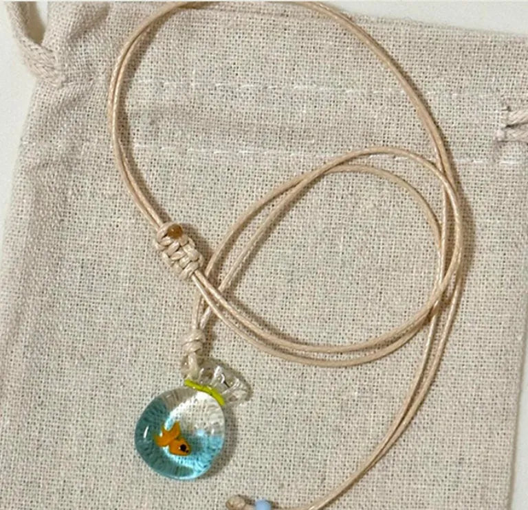 Women's necklace with coloured glaze joker pendant on a beige cotton and linen clavicle chain.