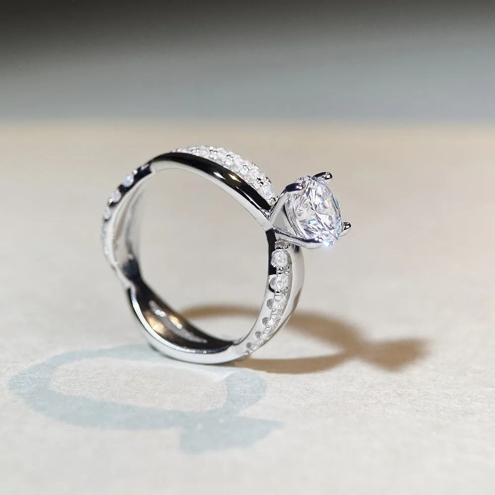 Silver ring with twisted arm design and a 1 karat moissanite stone in a four-claw setting.