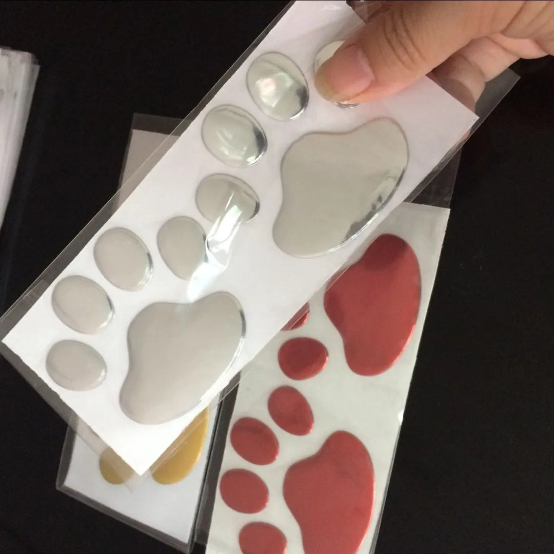 Pair of 7cm long PVC car stickers with a hand-shaped brush and dog footprints design in black, red, silver, and gold colour options.