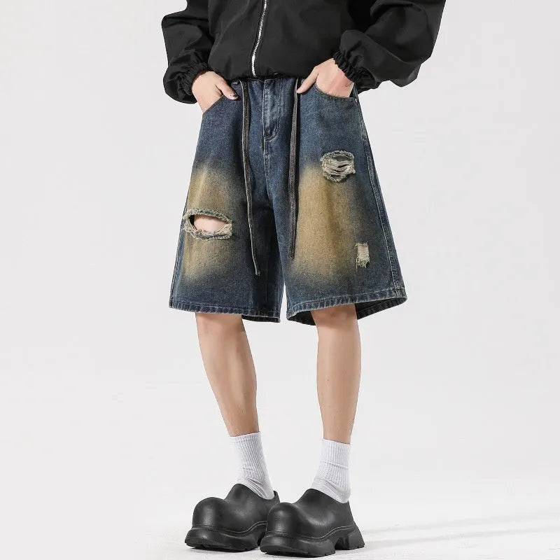 Man wearing retro blue loose fit ripped denim jeans with distressed details.