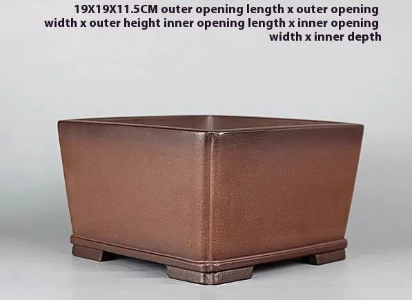 Handmade brown antique purple clay flower pot for indoor plants on a desktop.