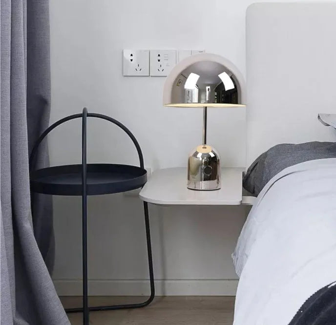 Mushroom-shaped metal table lamp in rose gold finish on a wooden table.