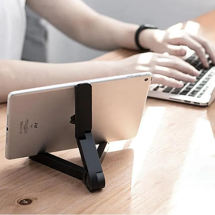 Black foldable aluminium tablet holder showing adjustable stand in open and closed positions on a desk.