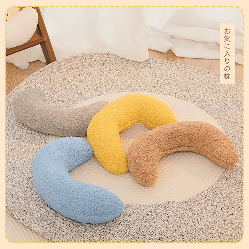 Blue U-shaped cat pillow with an adjustable fabric collar on a grey sofa.