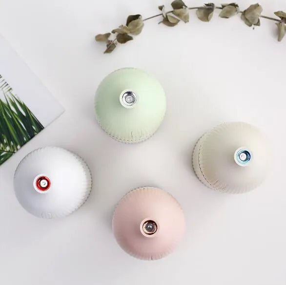 White ultrasonic aromatherapy diffuser and humidifier with 300ml capacity, USB port, and LED light on a wooden surface.