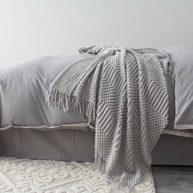 Small light grey polyester throw blanket folded on a sofa