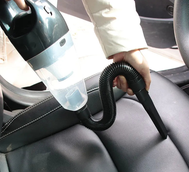 Orange handheld car vacuum cleaner with nozzle attached, next to its 12V cigarette lighter plug and additional accessories.
