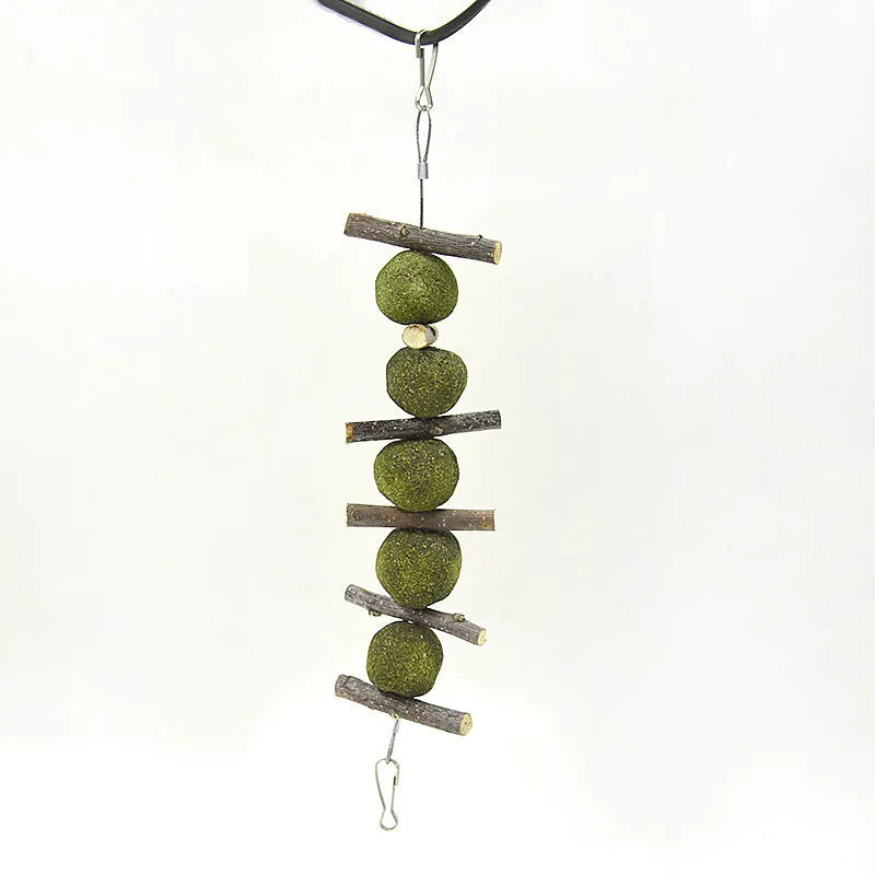 Natural grass balls and apple branches hanging chew toys for small pets on a cage bar