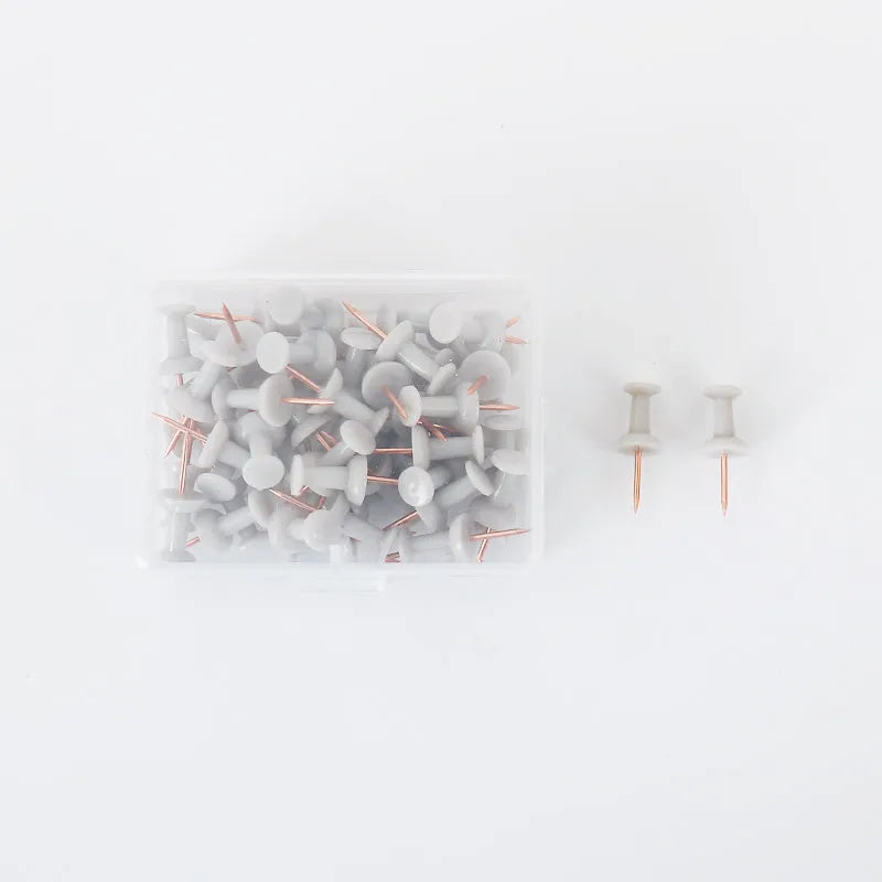 50-piece pack of Morandi colour push pins with three different pin head styles on a cork board.