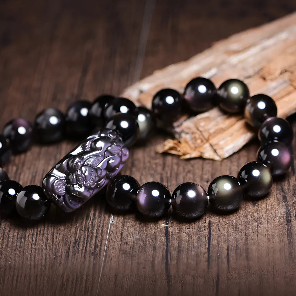 Polished icy obsidian crystal Pi Xiu bracelet with geometric ethnic style on adjustable cord.