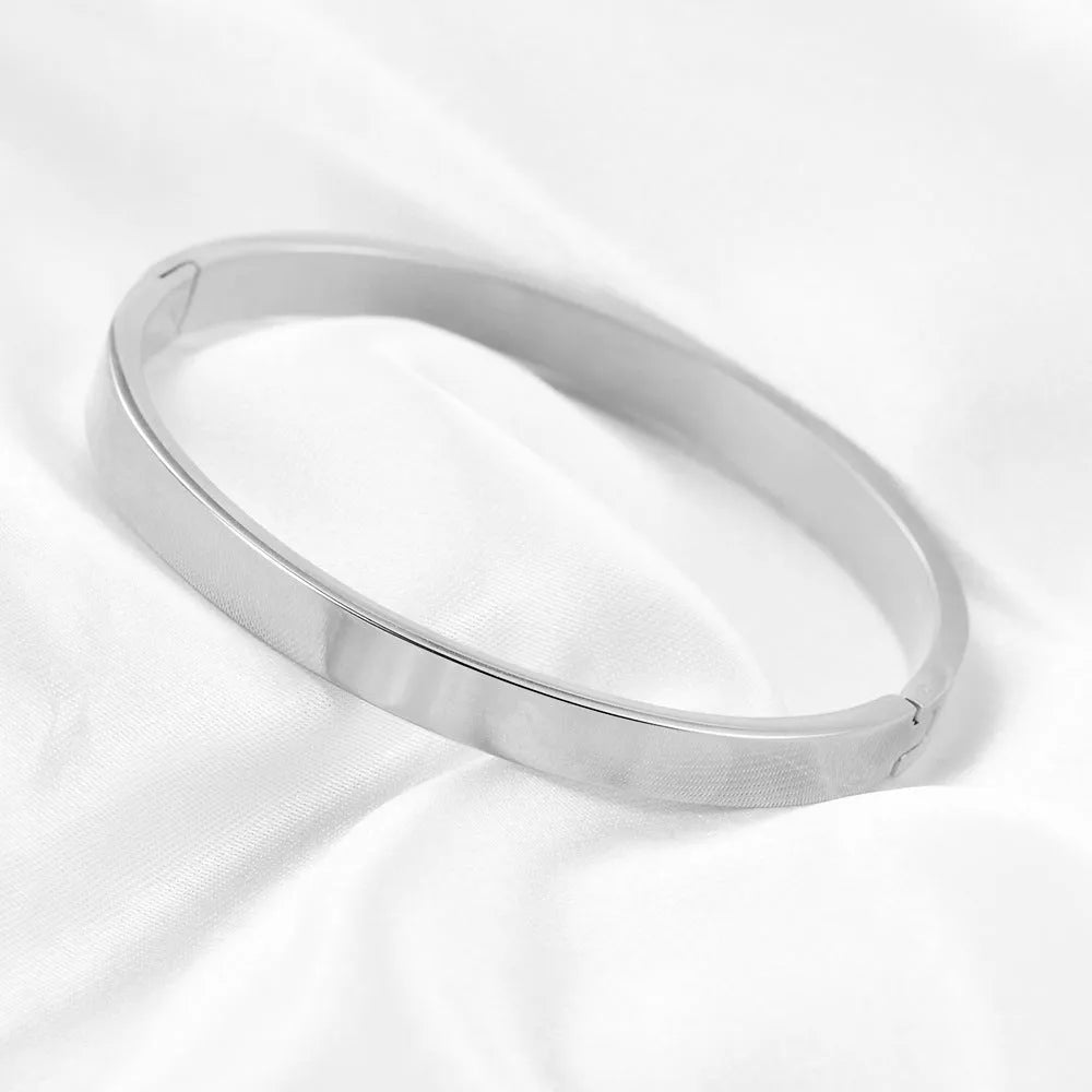 Polished stainless steel snap bracelet with oval links on plain background