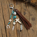 Alloy cross pendant keychain with leather rope and tassel in colour XY-3669 on a wooden surface