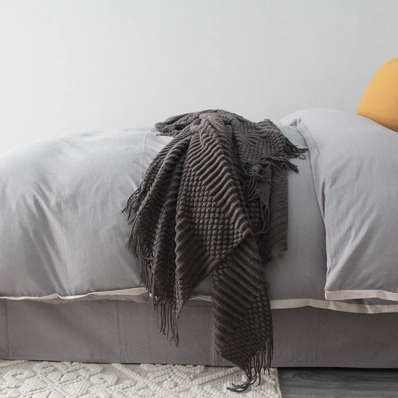 Small light grey polyester throw blanket folded on a sofa