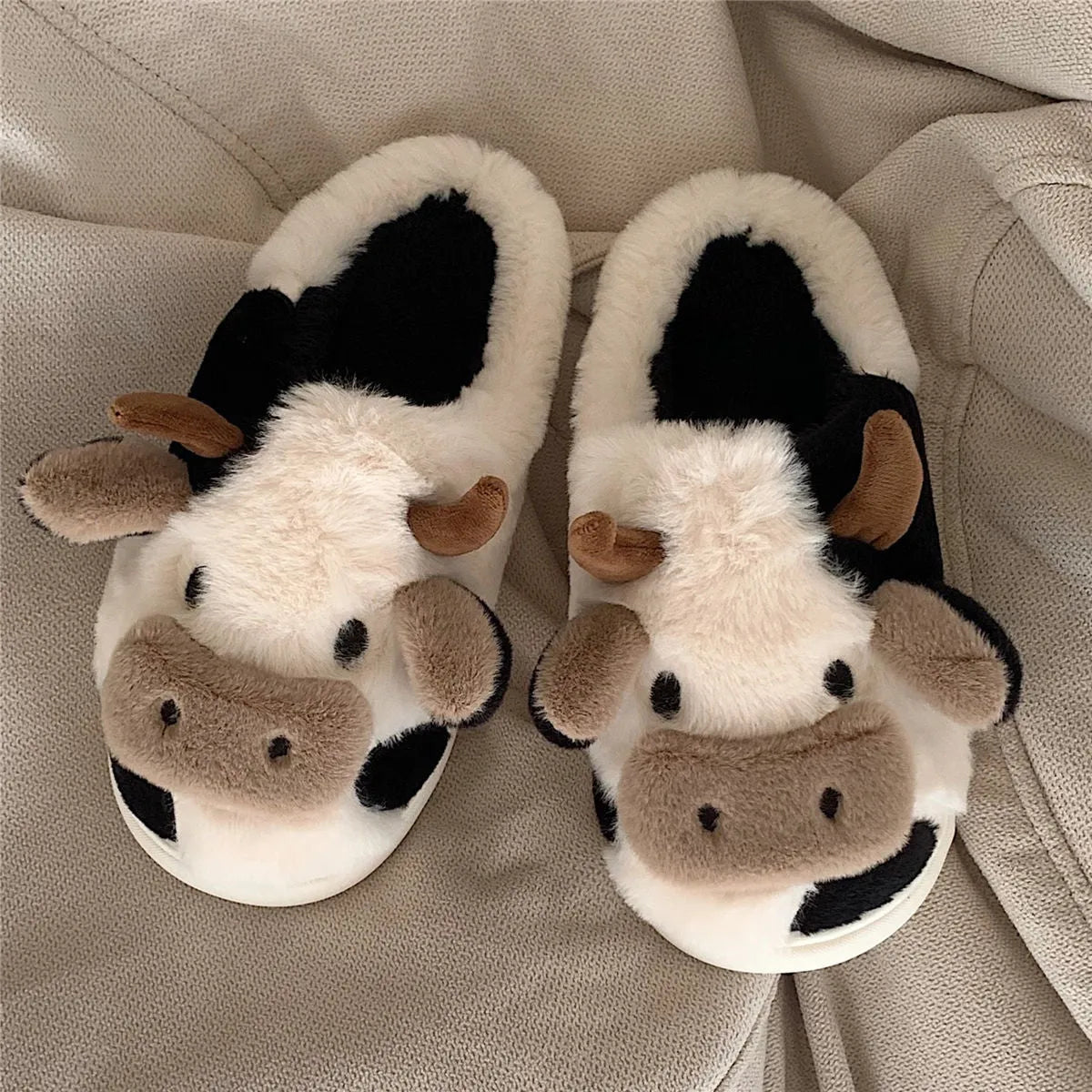 White cartoon cow plush slippers for women with a textured anti-slip sole.