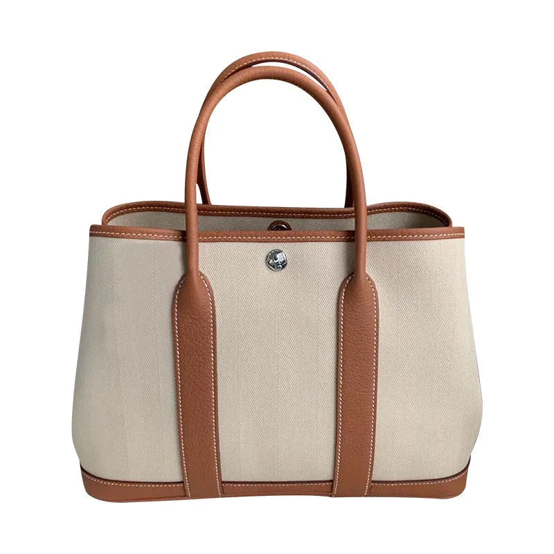 Women's canvas tote bag with genuine leather trim in bucket shape showing internal zip compartments