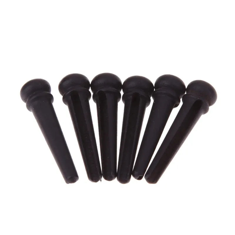 Six matt black ebony folk guitar bridge pins with 5.3mm bayonet diameter on a plain background.