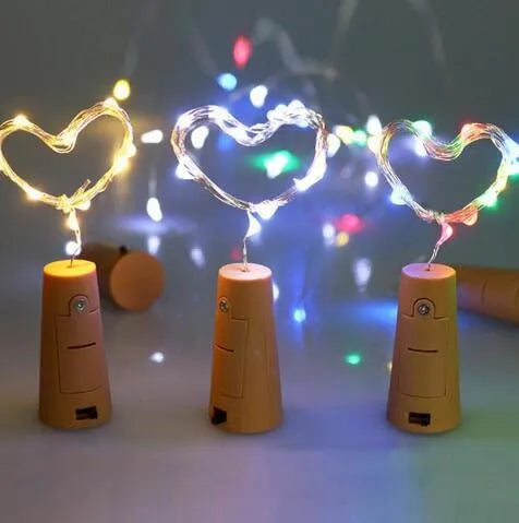Copper wire LED string light with bottle stopper illuminated in a glass wine bottle.