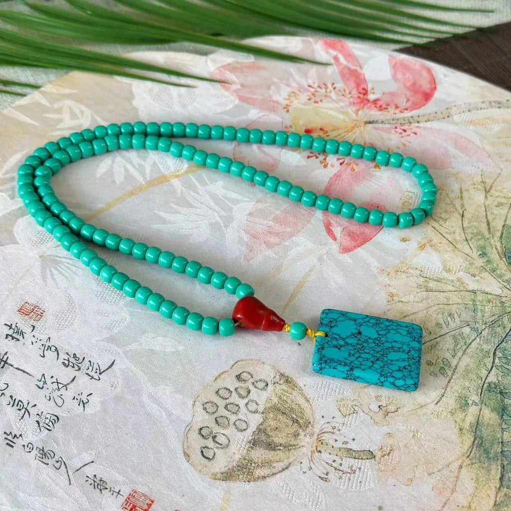 Turquoise lucky pendant necklace with hand-woven mesh flower stone design on a ball bead chain.