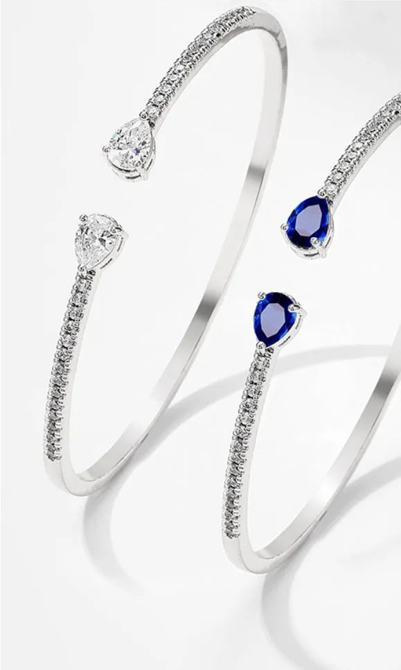 Close-up of a simple copper bracelet with inlaid blue zircon stones on a white background.