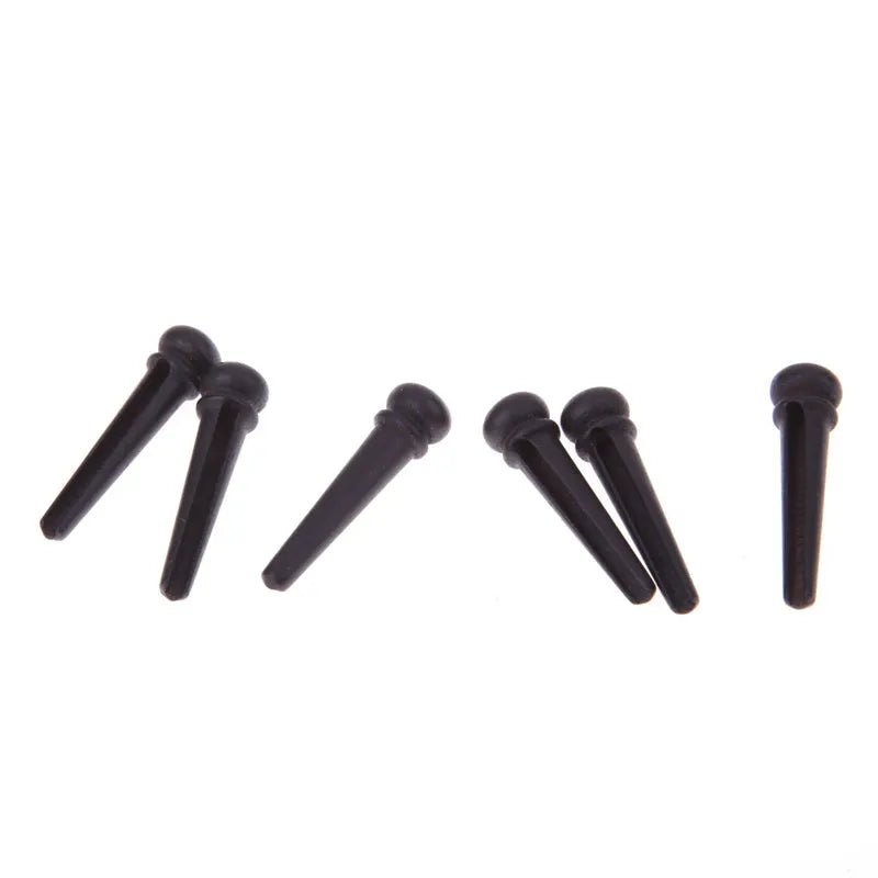 Six matt black ebony folk guitar bridge pins with 5.3mm bayonet diameter on a plain background.
