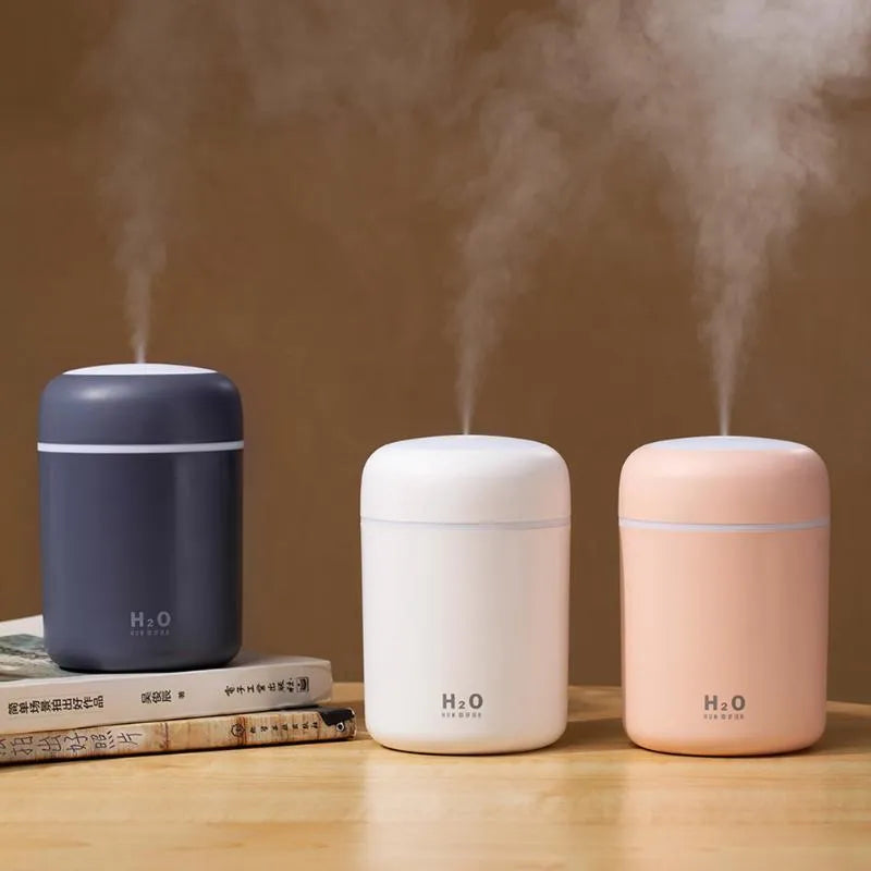 Pink, white or navy blue USB mini humidifier with colourful lights on desk surface