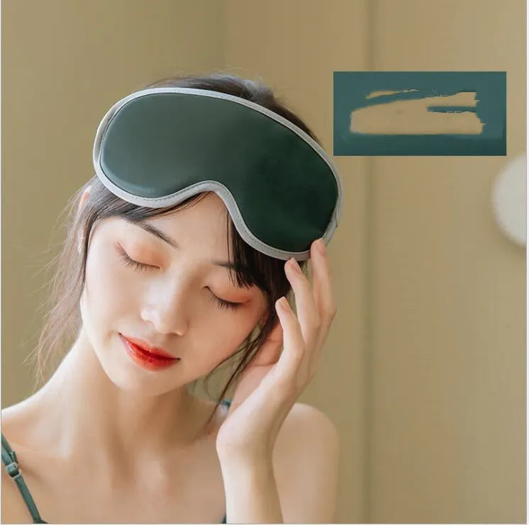 Green portable eye SPA mask with suede shell on a table, showing USB port and steam vents.