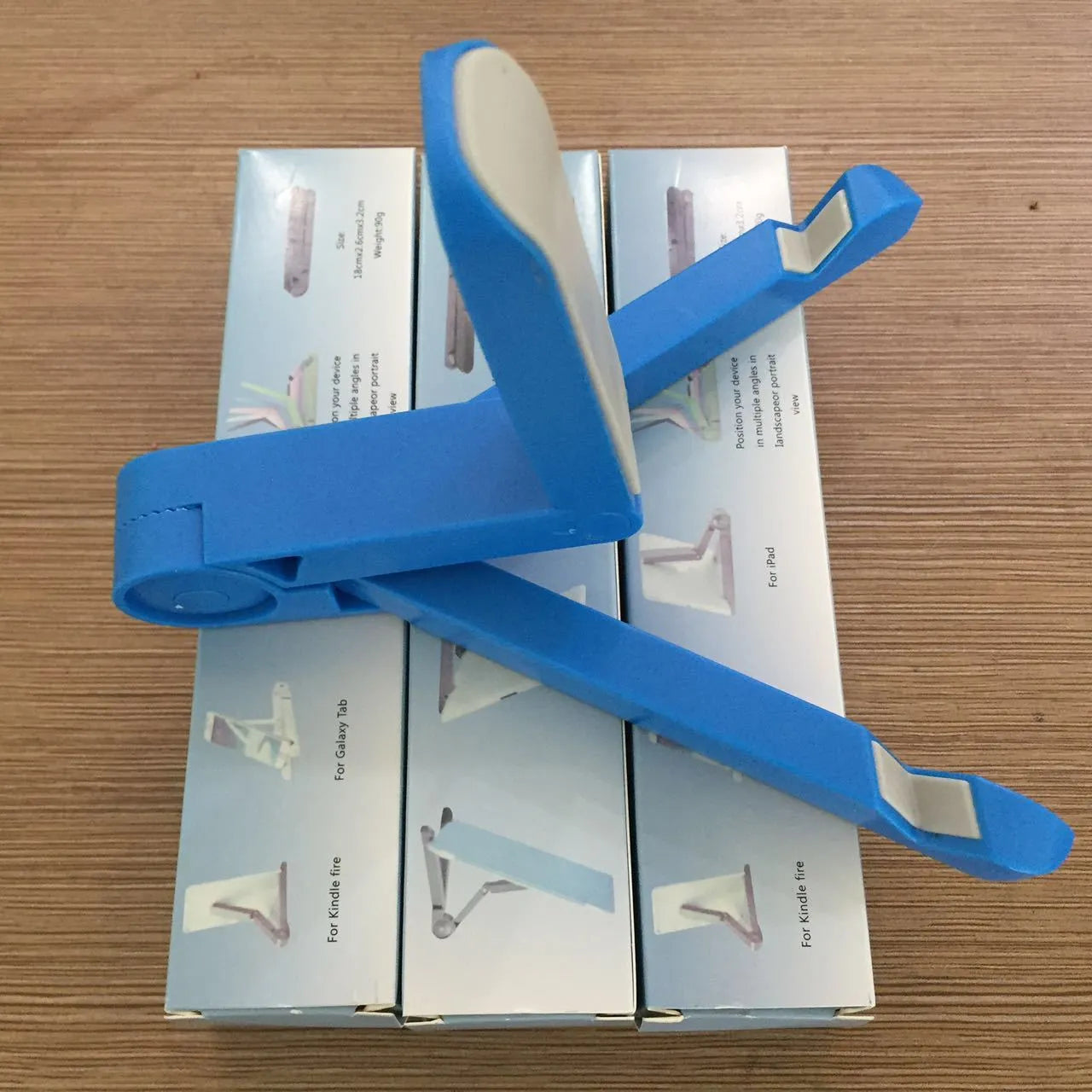 Black foldable aluminium tablet holder showing adjustable stand in open and closed positions on a desk.