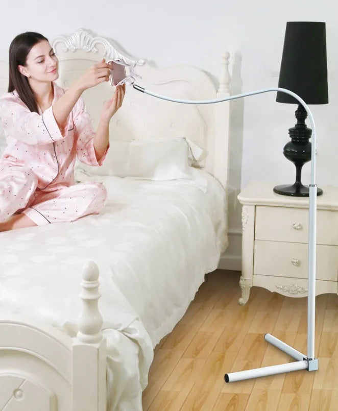 Black bedside mobile phone holder mounted on a bed frame with a phone securely clipped in place.