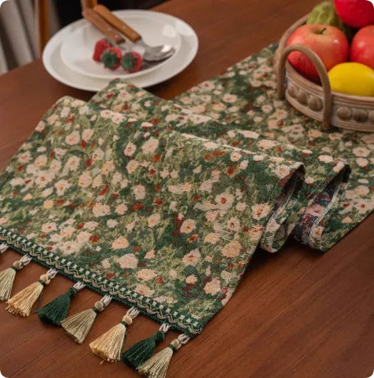 Long decorative table runner with handwoven tassels in a blue ginkgo leaf pattern on a wooden table.