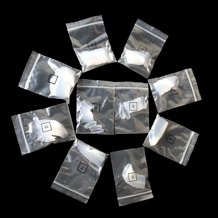 500 clear acrylic false nails in various sizes spread out on a table