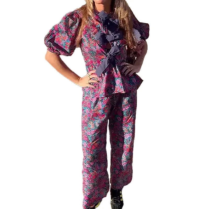 Women's floral print tie-neck blouse and trousers suit with puff sleeves.