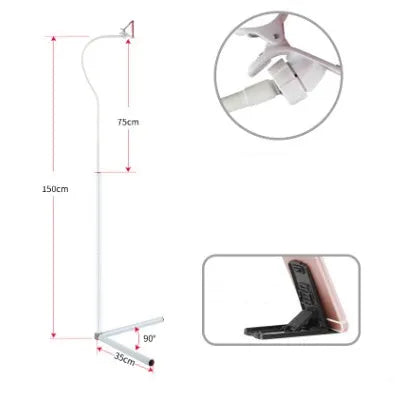 Black bedside mobile phone holder mounted on a bed frame with a phone securely clipped in place.