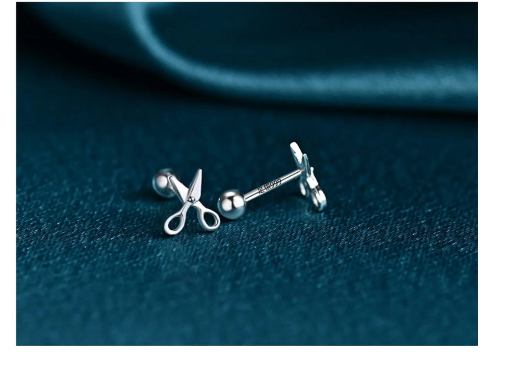 A pair of silver ear nail earrings with a mini scissors screw design and screw-back closures.