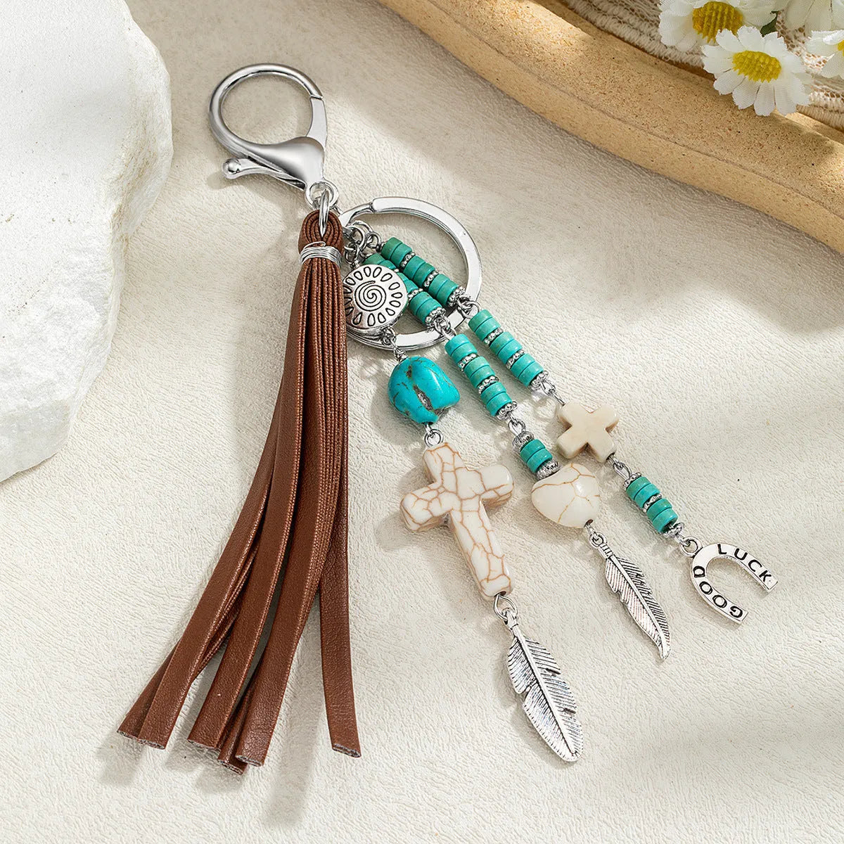 Alloy cross pendant keychain with leather rope and tassel in colour XY-3669 on a wooden surface