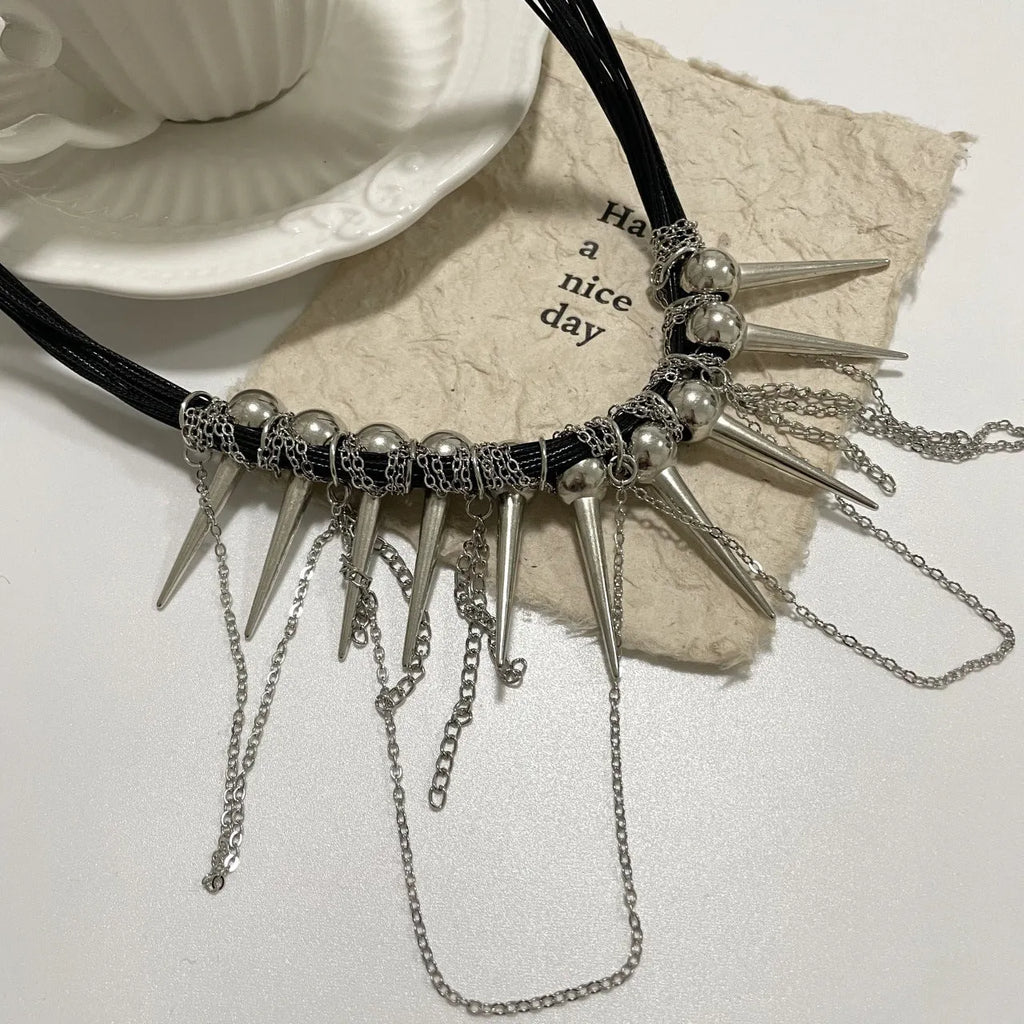 Leather necklace with winding round beads, tassel detail, and electroplated point rivets in casual style.