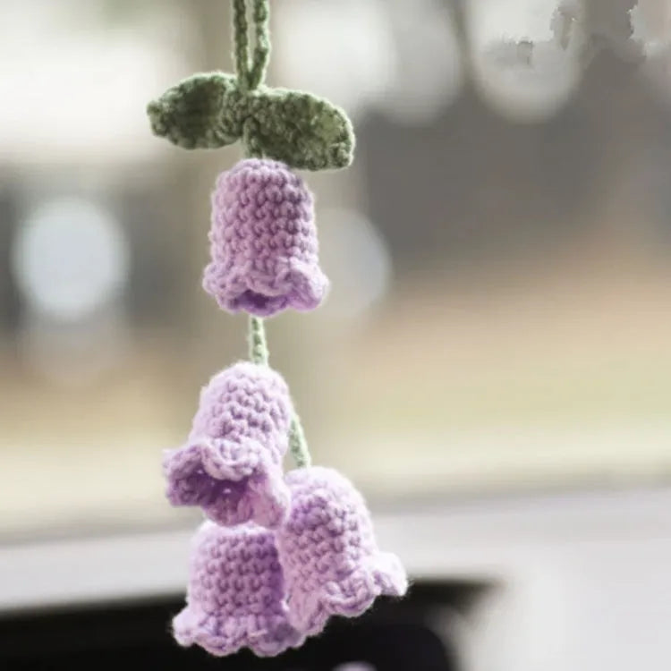 Green and white knitted wool car plant decoration hanging from a rope.