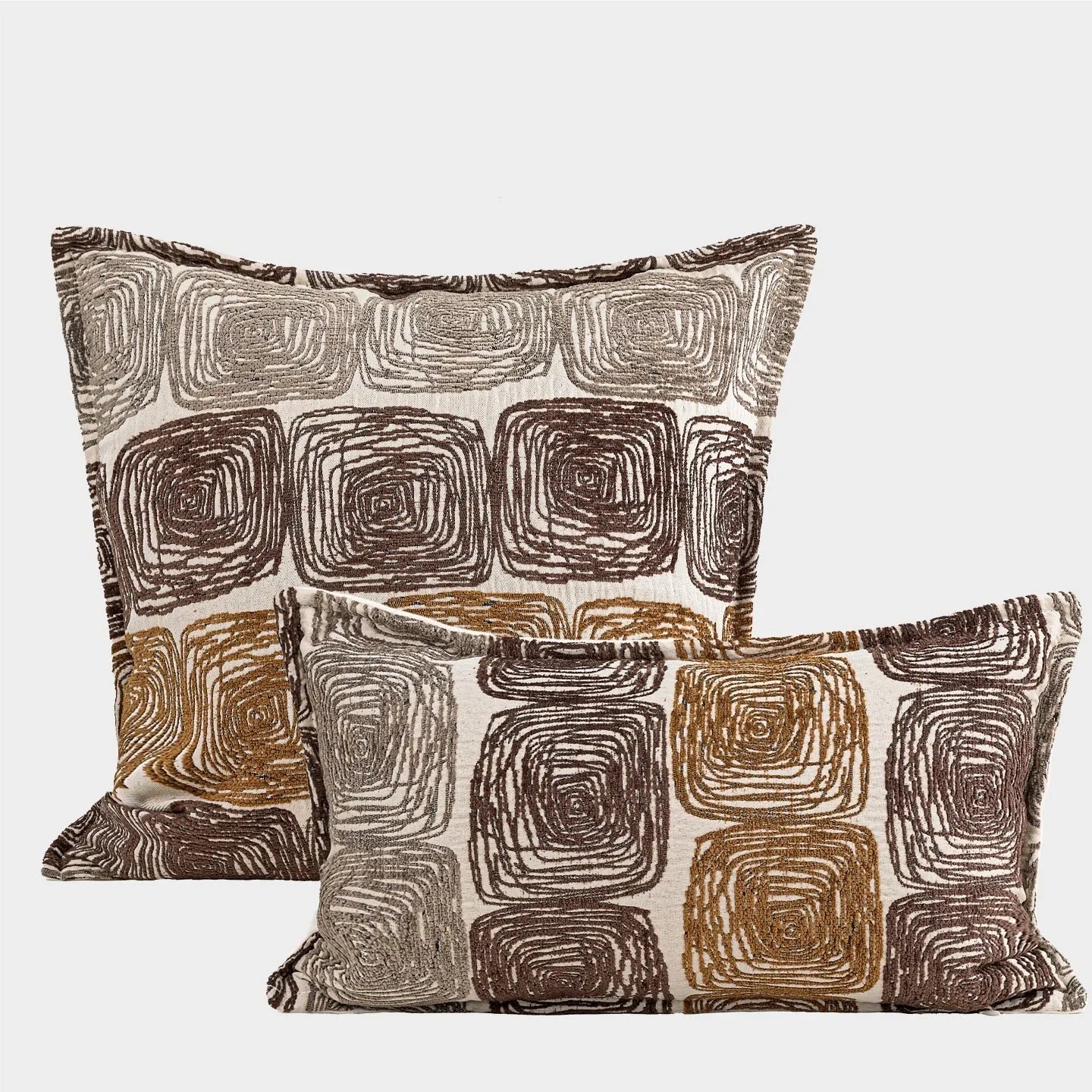Cream and coffee-coloured abstract coil pattern on two pillow covers: one square, one rectangular.
