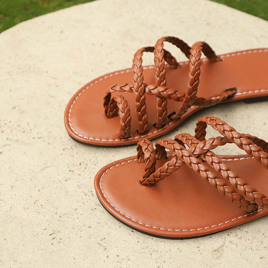 Women's flat woven sandals with clip-toe design in black, shown on a white background.