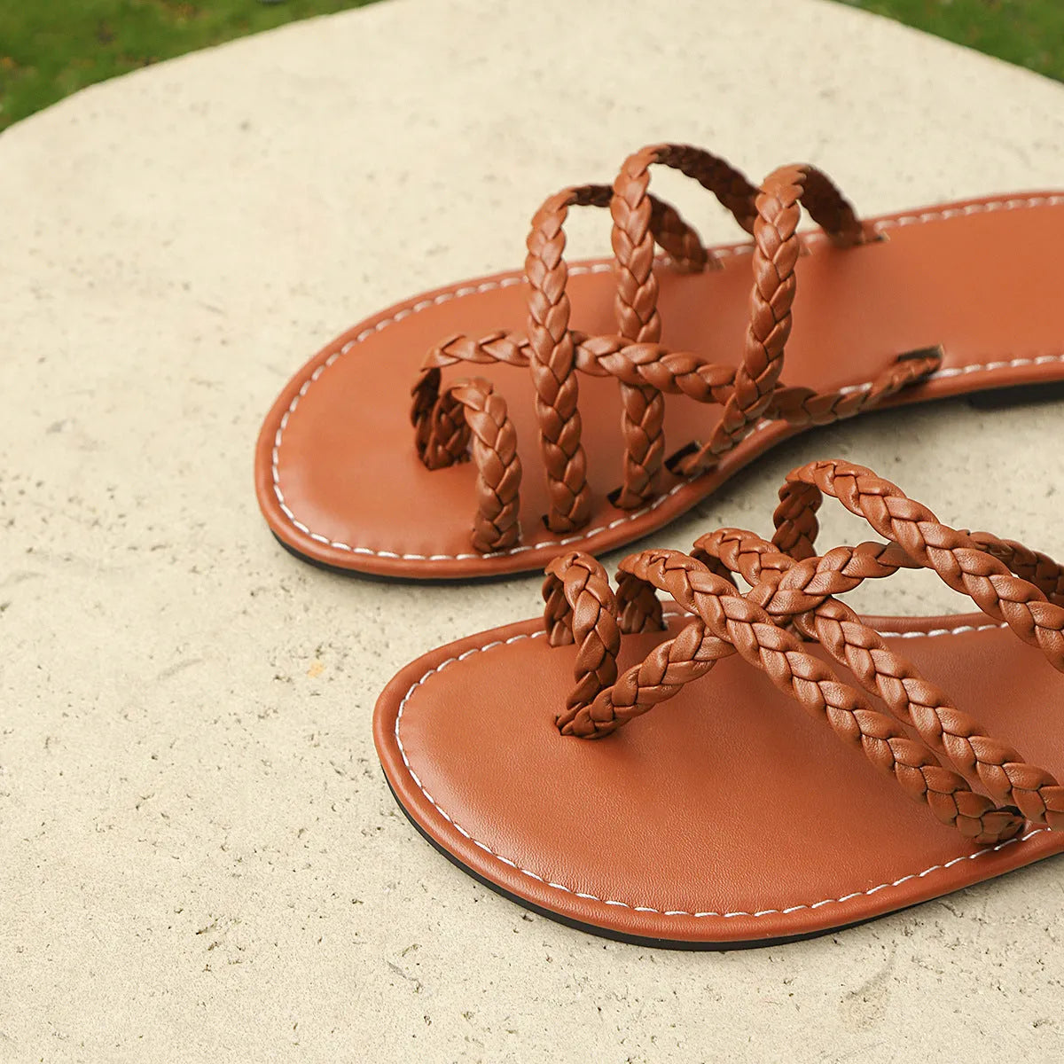 Women's flat woven sandals with clip-toe design in black, shown on a white background.